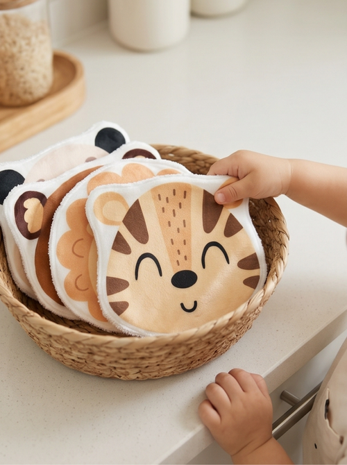 Panier tressé rempli de grands cotons lavables bébé en forme d'animaux de la jungle, avec un motif tigre sur le dessus. Lingette lavable réutilisable et artisanale pour la toilette.
