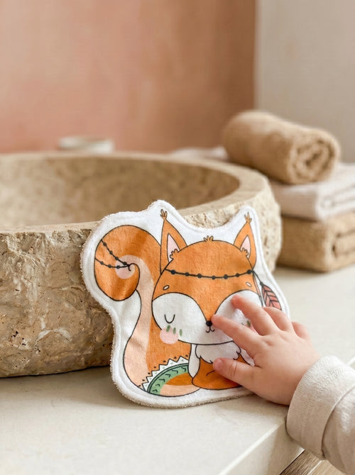 Grand coton lavable en forme d'écureuil style bohème posé à côté d'une vasque en pierre. Lingette lavable bébé artisanale et réutilisable pour la toilette des enfants.